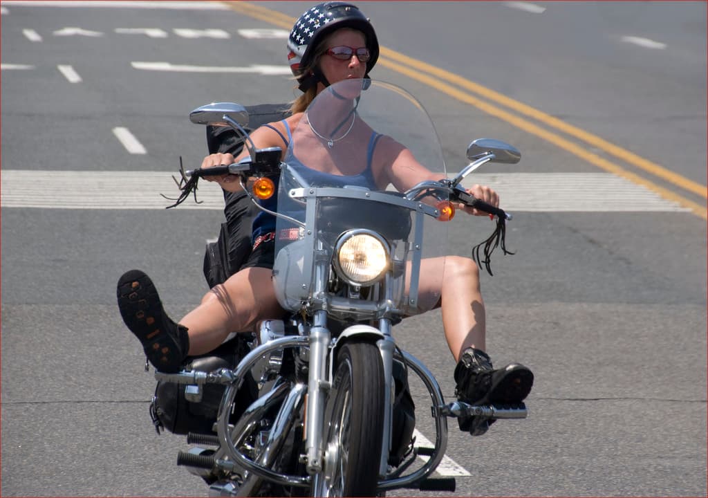 Eine Frau fährt ein Fahrrad auf einer Straße und trägt einen schwarzen Helm.