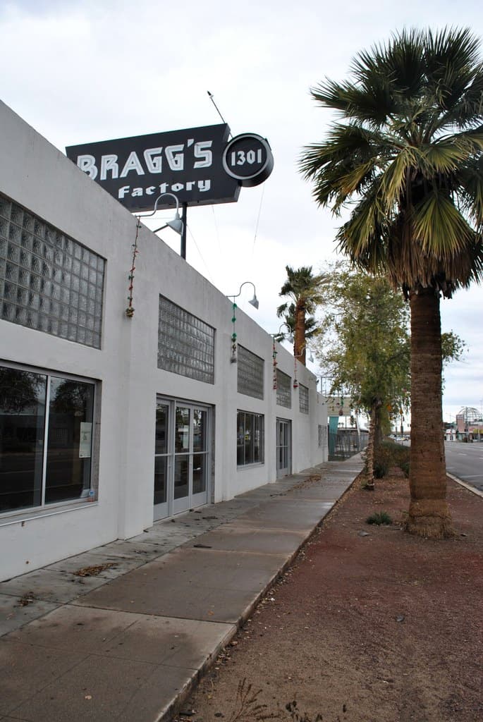 Ein Gebäude mit einer Fahne, auf der "Braggs Factory" steht, umgeben von Bäumen.