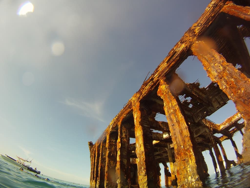 Ein Schiff befindet sich auf dem Wasser in der linken unteren Ecke, mit einem hölzernen Dock auf der rechten Seite.