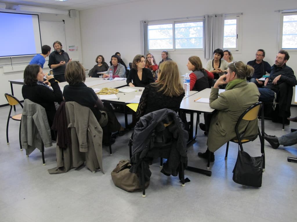 Eine Gruppe von Menschen, die sich unterhält, mit zwei Personen im Hintergrund, die miteinander sprechen.