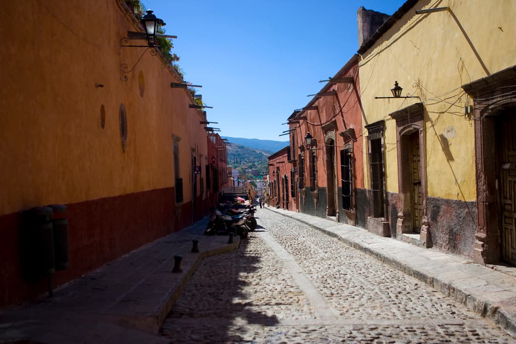 Eine leere Straße mit zahlreichen geparkten Fahrrädern, umgeben von mehreren Gebäuden, mit einem prominenten Gebäude im Vordergrund.