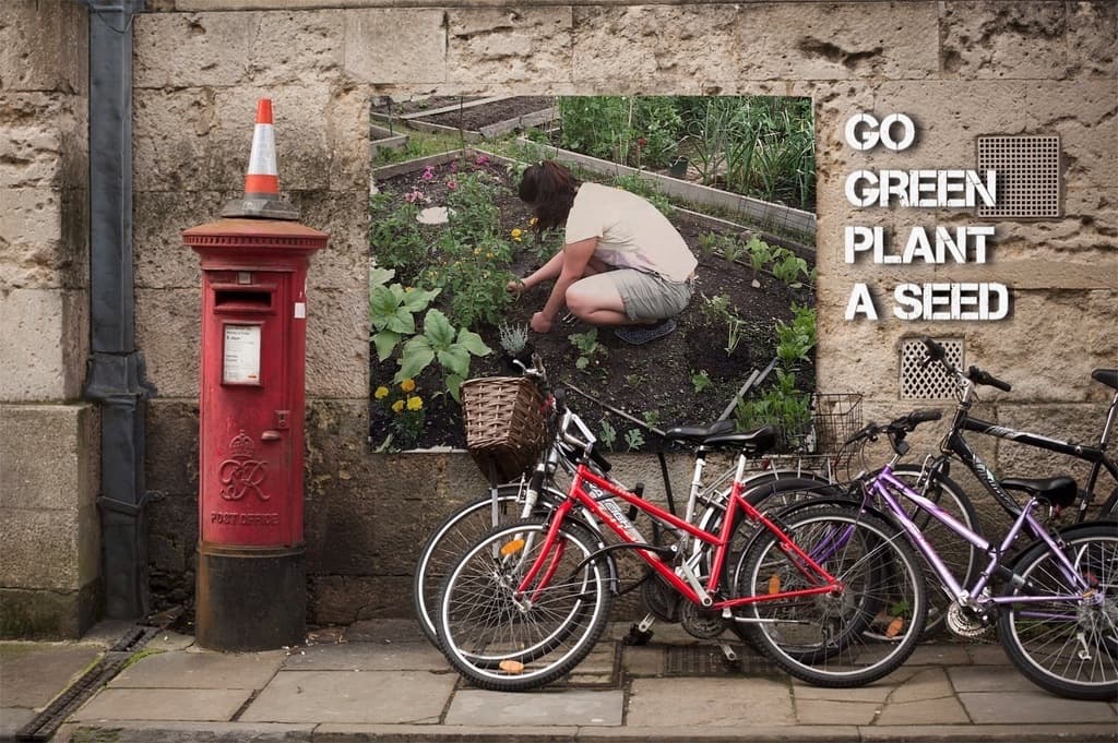 Fahrr"ader in der N"he einer Briefkasten mit einer Sicherheitst"ne darauf, eine Wand mit einem Plakat und Text im Hintergrund und ein Weg am Boden.