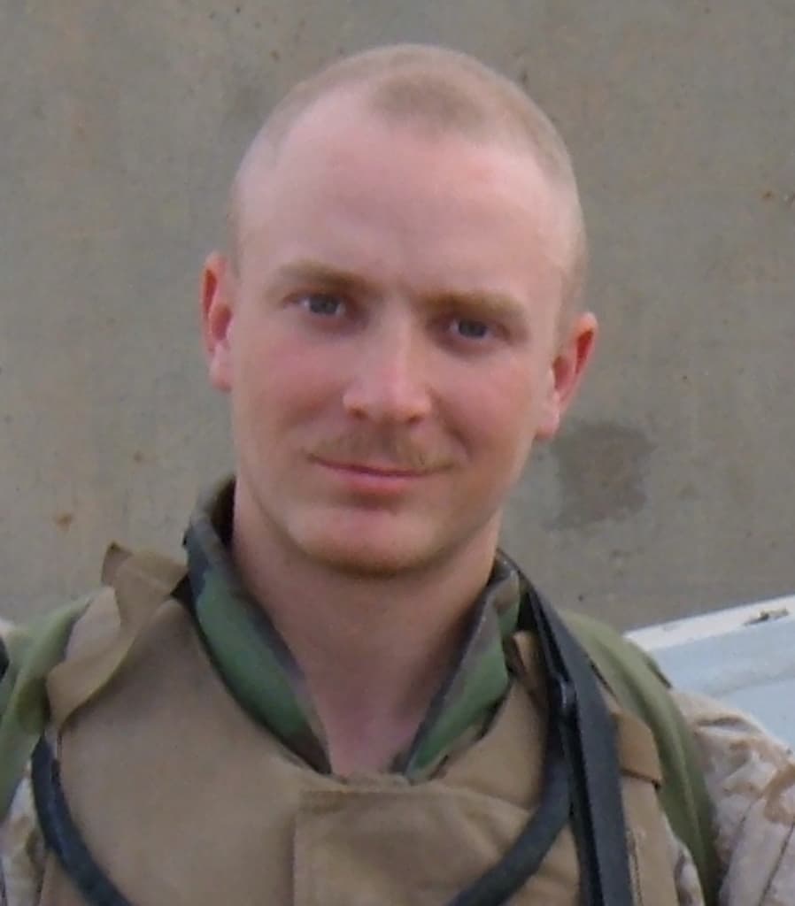 Ein Soldat, der vor einer Wand lächelt.