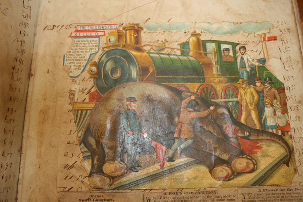 Ein Buch mit Text und einem Bild eines Elefanten, einer Eisenbahn auf einer Bahnstrecke, einer Gruppe von Menschen und Wolken oben.