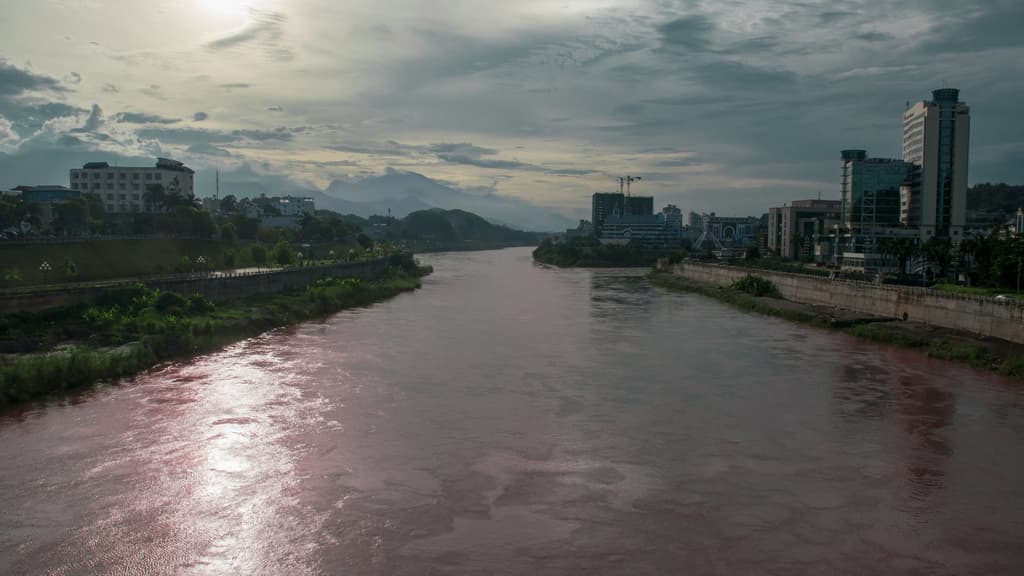 Ein breiter Fluss mit zahlreichen Gebäuden und Pflanzen an seinen Ufern.