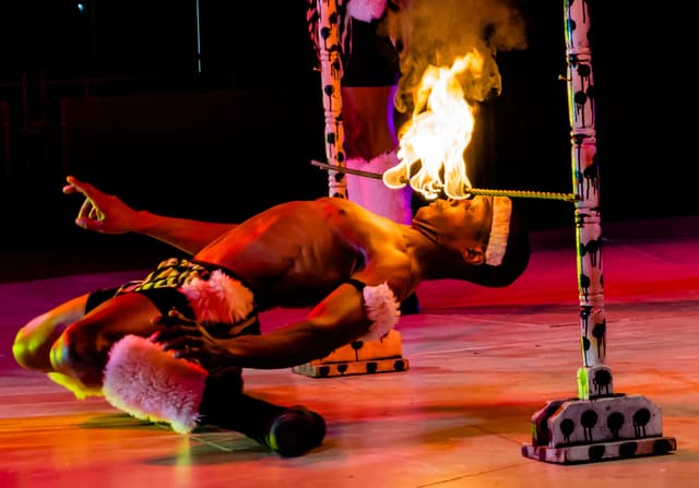 Eine Person schaut auf ein Feuer, das auf einem Stab an Stangen befestigt ist.