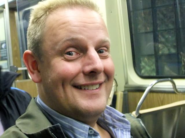 Eine Person steht vor einem Zug mit einem Fenster auf der rechten Seite.