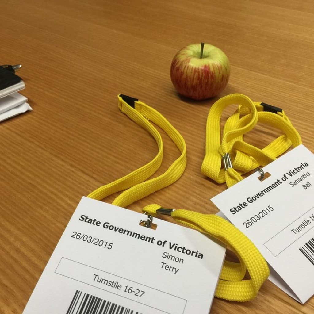 Ein Tisch mit zwei Ausweisen, einem Apfel und einem schwarzen Gegenstand.