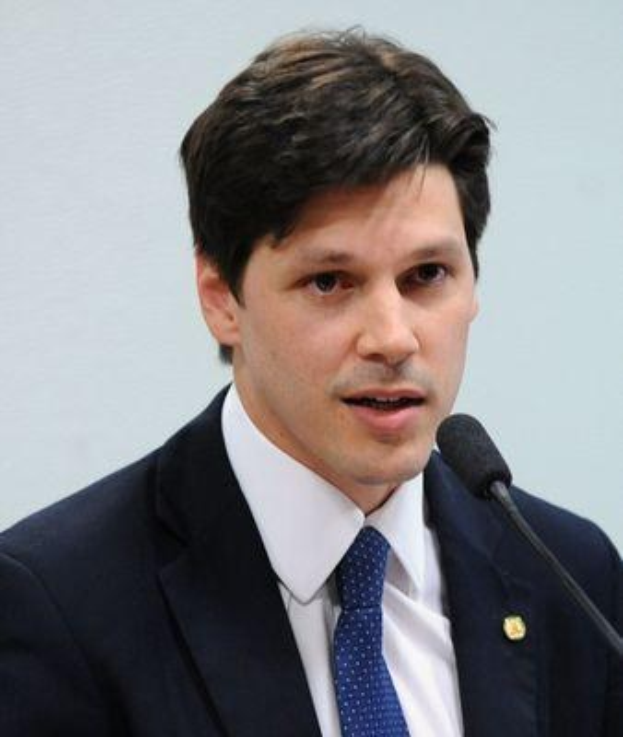 Ein Mann im Anzug spricht in ein Mikrofon an einem Rednerpult, wahrscheinlich um die Genehmigung eines Gesetzes durch die Regierung zu kommentieren.