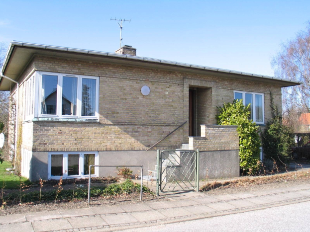 Ein frei stehendes Bungalow mit zwei Schlafzimmern zum Verkauf in St Johns Wood, Swindon, mit einem Dach, Fenstern, einer Tür, einer Treppe, einem Metallzaun, Pflanzen, Gras, Bäumen, einer Satellitenschüssel und einer bewölkten Himmel.