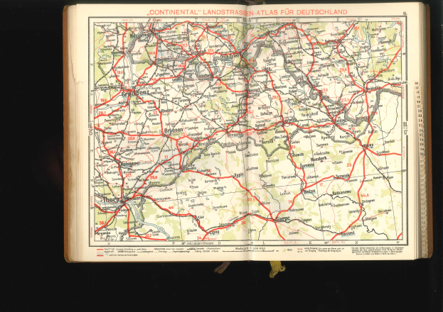 Offenes Buch mit einem detaillierten Straßen- und Autobahnplan von Deutschland auf einem schwarzen Hintergrund.