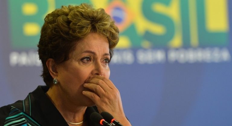 Brasiliens Präsidentin Dilma Rousseff spricht bei einer Pressekonferenz in Rio de Janeiro vor einer Tafel mit Text und mehreren Mikrofonen.