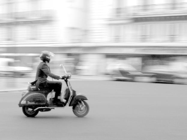 Eine Person fährt Roller auf einer Straße.