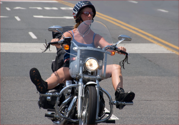 Eine Frau fährt ein Fahrrad auf einer Straße und trägt einen schwarzen Helm.