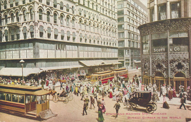 Altes Schwarz-Weiß-Foto einer belebten Stadtstraße mit Fußgängern, Kutschen, Laternenmasten und mehrstöckigen Gebäuden; gefaderter Text erscheint unten.