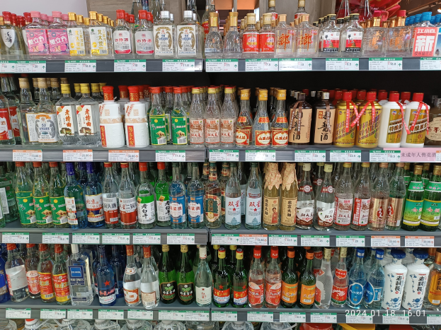 Vitrine mit verschiedenen Alkoholflaschen, jede mit Etiketten und Preisschildern, unter Deckenbeleuchtung in einer Spirituosenladen-Atmosphäre.