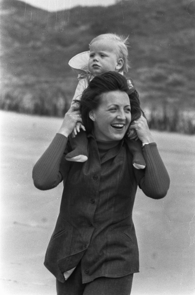 Eine Frau, die strahlend ihr Baby hält, vor einem sanft unscharfen Hintergrund, der einen träumerischen Effekt erzeugt.