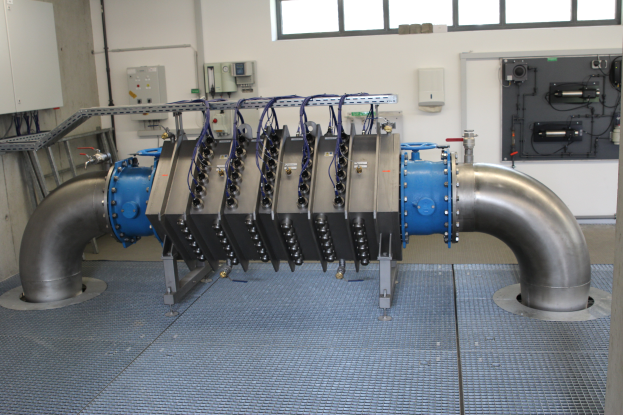 Ein großes Wärmetauschergerät in einem Gebäude, mit einem Boden, einer Wand und Fenstern, das an verschiedene Komponenten und Drähte angeschlossen ist.