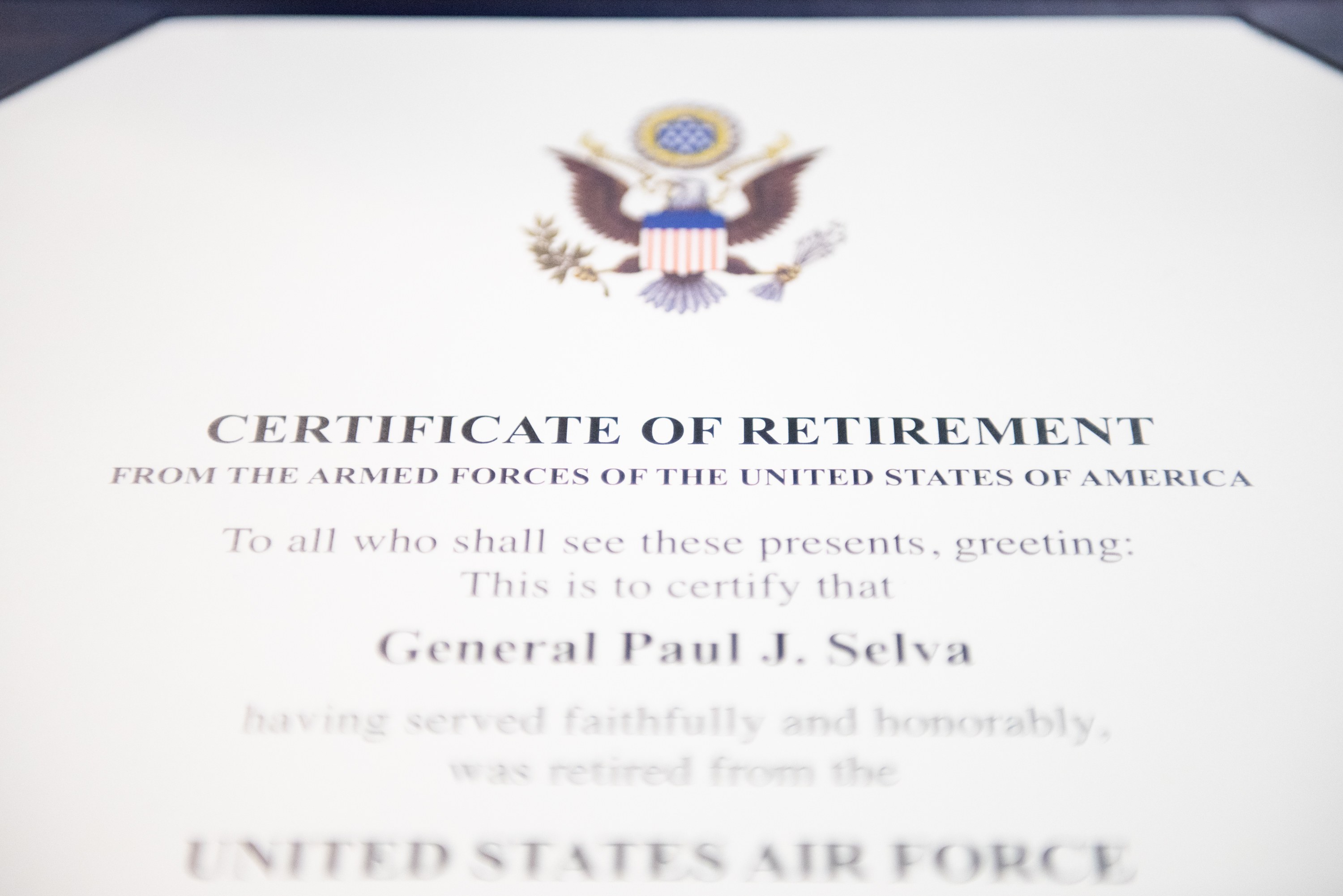 Rahmenurkunde für den Ruhestand der United States Air Force mit blauem Rand, zentralem Stern in einem Lorbeerkranz und einem 'Ruhestand'-Banner auf einem Schild-Logo, alles in schwarzer Schrift.