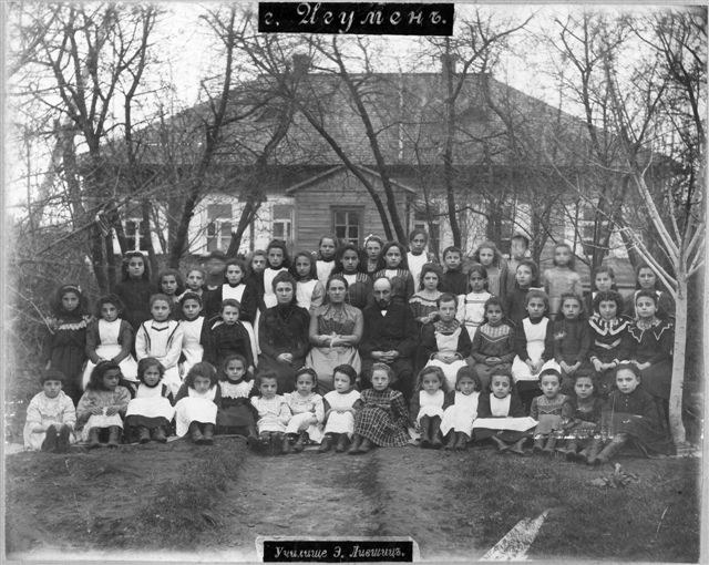 Schwarz-weiß-Foto von Kindern, die vor einem Fenster mit Text 'Jugoslawien, die erste Schule der Welt' posieren.
