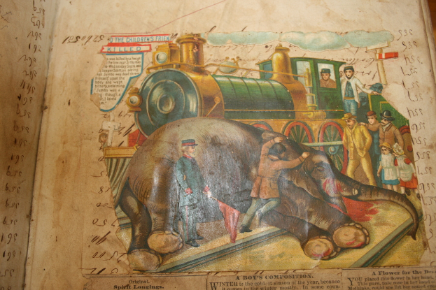 Ein Buch mit Text und einem Bild eines Elefanten, einer Eisenbahn auf einer Bahnstrecke, einer Gruppe von Menschen und Wolken oben.