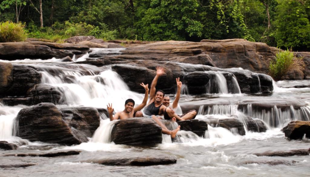 Eine Gruppe lachender Männer, die gemeinsam vor Bäumen, Pflanzen, Wasserfällen und Felsen posen.