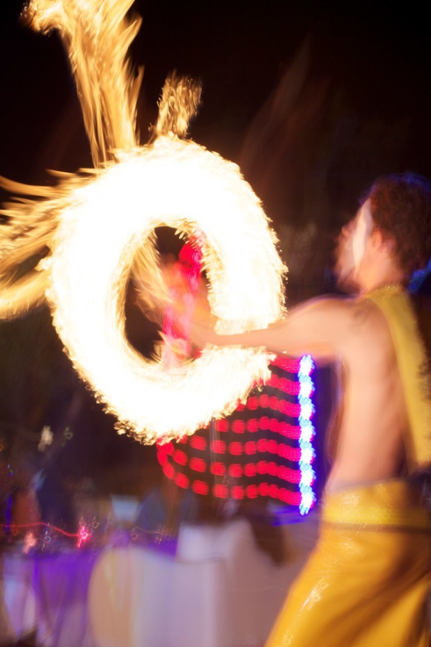 Ein Mann spielt mit dem Feuer, mit Lichtern im Hintergrund.