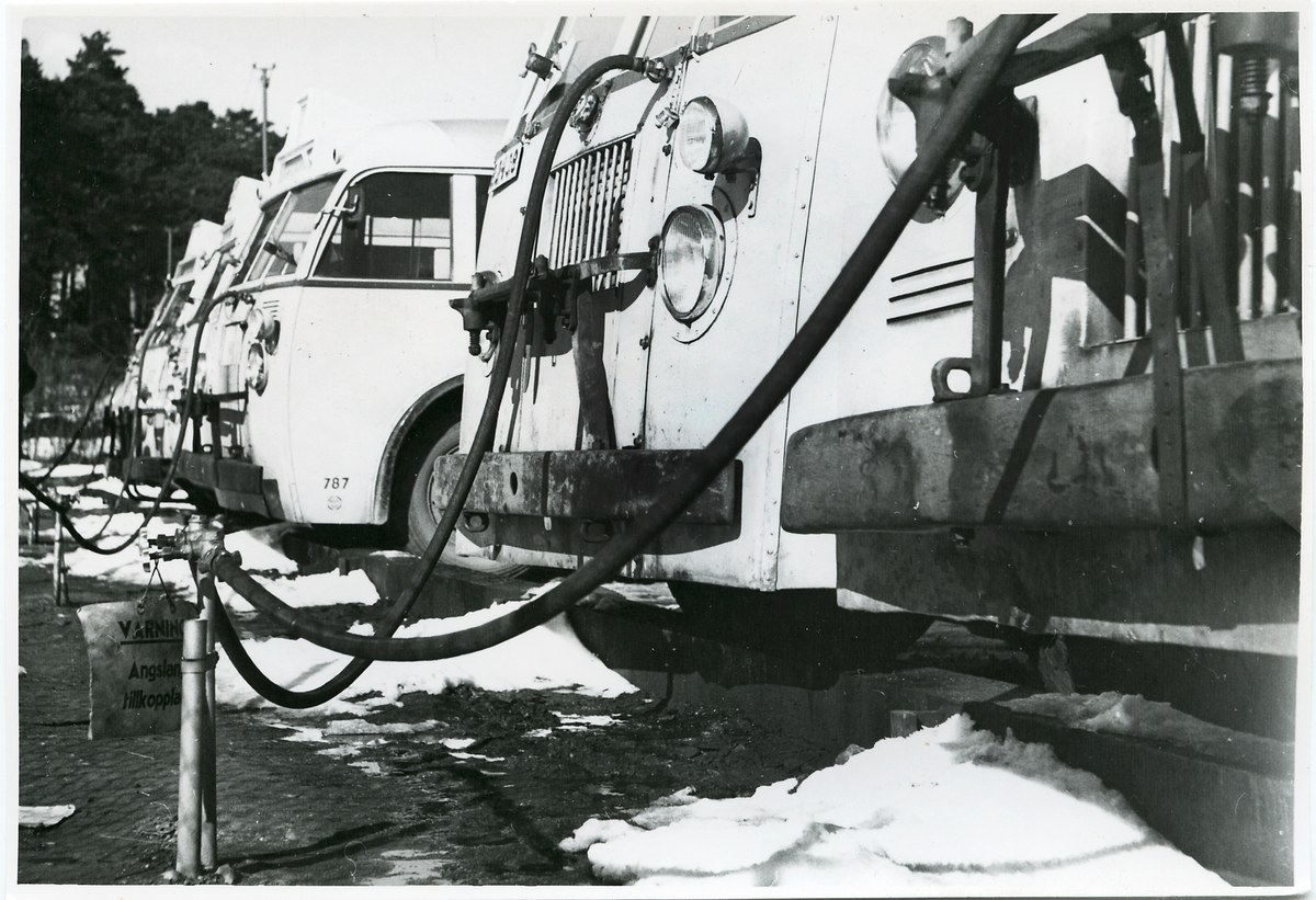 Schwarz-weißes Foto eines Lkw, der auf Schnee geparkt ist und von Bäumen umgeben ist, mit einem sichtbaren Vorderrad.
