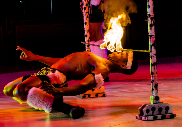 Eine Person schaut auf ein Feuer, das auf einem Stab an Stangen befestigt ist.