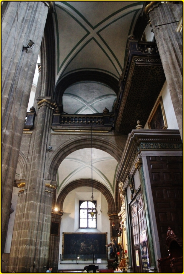 Ein Innenblick in einen Palast mit Schränken, beleuchteten Säulen, Wandskulpturen, einem großen Foto Rahmen und einer von der Decke hängenden Lampe.