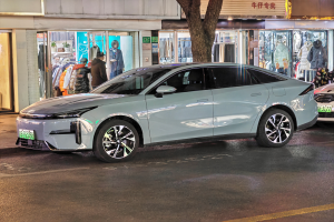 Ein Mitsubishi Lancer EV Elektroauto, das nachts auf einer Straße geparkt ist, umgeben von Gebäuden, Geschäften, Schaufensterpuppen, Schildern und Lichtern.