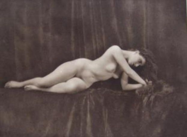 Eine nackte Frau auf einem Tuch liegend.