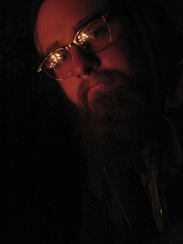Ein Mann mit einem großen Bart und Brille posiert vor der Kamera.