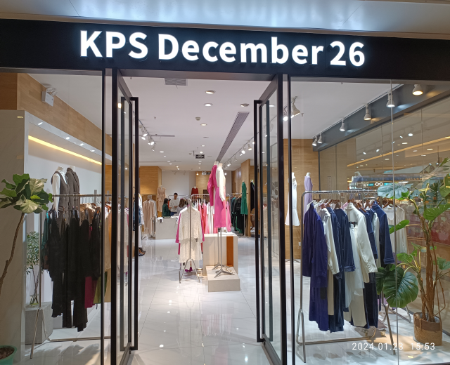 Das Innere eines KPS-Geschäfts am 26. Dezember in Singapur, mit Kleidung an Bügeln, bekleideten Schaufensterpuppen, Topfpflanzen, Glaswänden, Deckenlampen und einem Schild mit Text, wobei der Boden unten sichtbar ist.