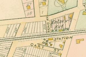 Alte Stadtkarte mit zahlreichen Gebäuden, nummerierten Grundstücken und Text, der als 'Land zur Verfügung' am unteren Rand bezeichnet ist.