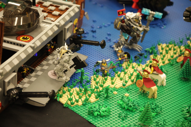 Lego-Schlossmodell mit verstreuten Lego-Teilen, einschließlich Spielzeugen, Pflanzen und anderen Gegenständen.