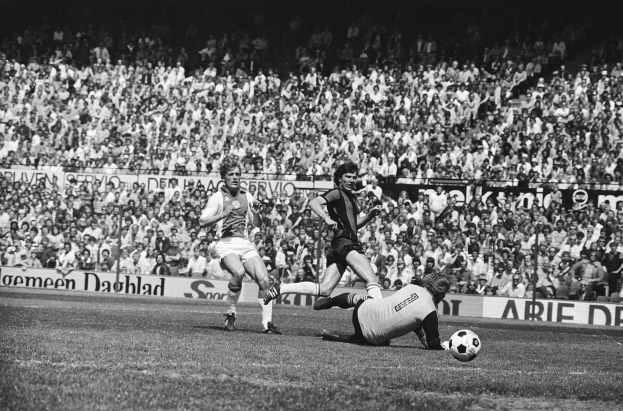 Schwarzes Foto von Fußballspielern im Einsatz auf einem Feld mit Zuschauern im Hintergrund und einem Bundesliga-Banner 1978-79 mit der Aufschrift "Ajax 1-1 Hannover 96."