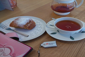 Ein Tisch mit einer Geldbörse, Schlüsselanhänger, Tasse, zwei Tellern, einer Gabel, einem Lebensmittel, einer Suppenschale und einem Löffel.