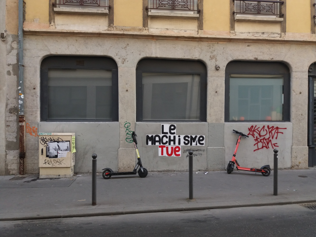 Zwei Roller auf der Straßenseite neben einem Gebäude mit Fenstern, Geländern und einem Rohr geparkt.
