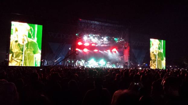 Ein Konzertbild mit einer Menge unten und großen Bildschirmen links und rechts.