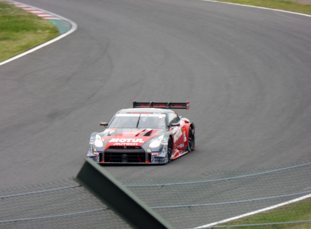 Ein Nissan GT-R Nismo GT3 Rennauto auf der Nürburgring 24 Stunden Rennstrecke, mit grünem Gras auf beiden Seiten des Asphalts.
