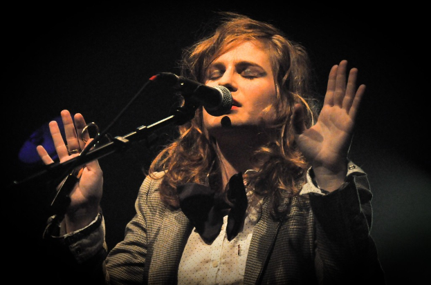 Eine Frau singt in ein Mikrofon mit einem schwarzen Hintergrund.