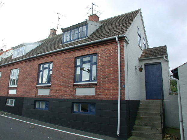 Ein dreigeschossiges Reihenhaus mit Dach, Fenstern, Türen, Treppe, Rohr, Wand, Baum und weiteren Objekten vor einem Himmelhintergrund in St Marys Road, St Margaret's, Swansea.