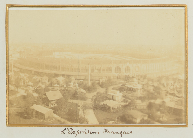 Altes Schwarz-Weiß-Foto eines Stadions in einer städtischen Umgebung, umgeben von Gebäuden, Bäumen und Strommasten, mit Text am unteren Rand.
