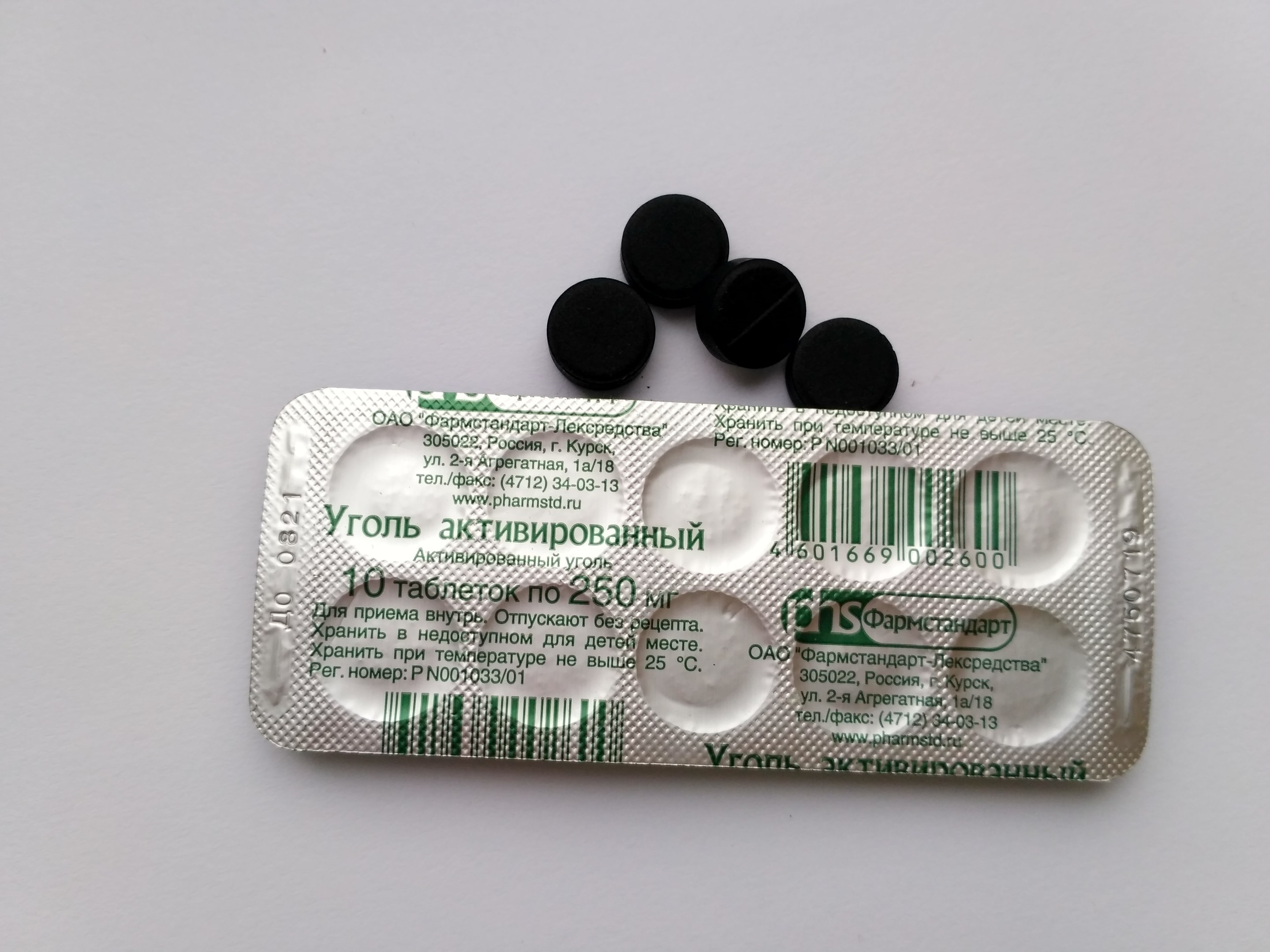 Ein weißer Tisch mit einer Blisterpackung schwarzer Pillen, auf dem Text und ein Barcode zu sehen sind.