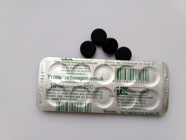 Ein weißer Tisch mit einer Blisterpackung schwarzer Pillen, auf dem Text und ein Barcode zu sehen sind.