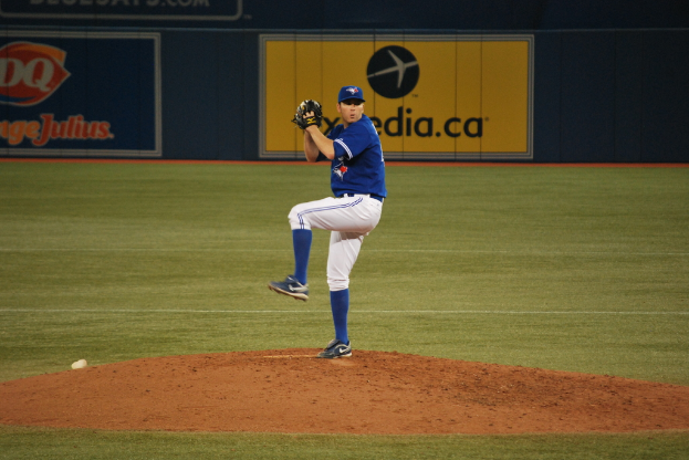 Ein Spieler steht auf dem Boden und hält einen Ball, mit einem großen Banner im Hintergrund, das Text und Bilder enthält.