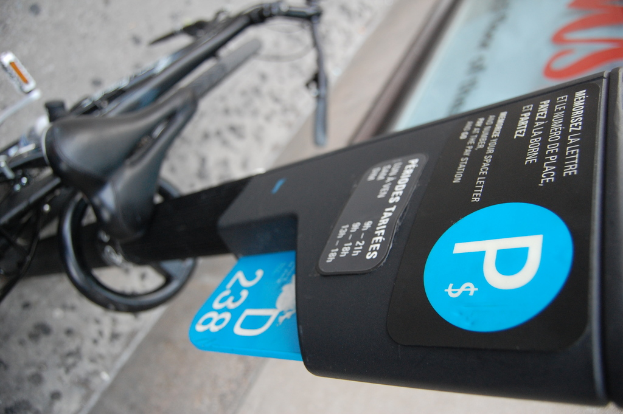 Ein Fahrrad steht auf dem Boden neben einem Parkscheinautomaten, mit einem Gehweg unten im Bild.