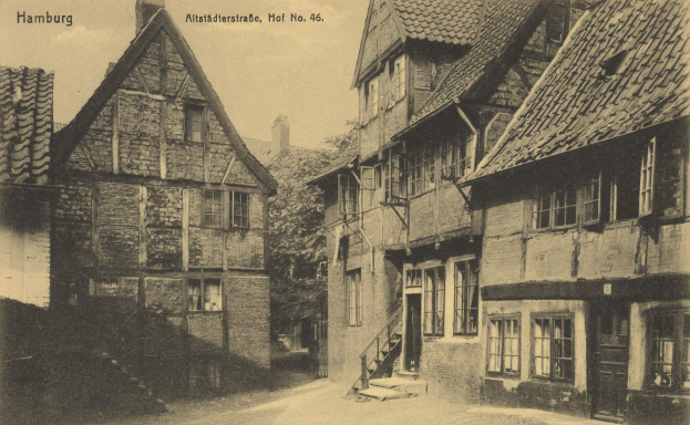 Ein altes Schwarz-Weiß-Foto einer Straße in Hamburg, Deutschland, mit Gebäuden mit Fenstern, Treppen mit Geländern, Bäumen und einem Himmel im Hintergrund, mit Text oben auf dem Bild.