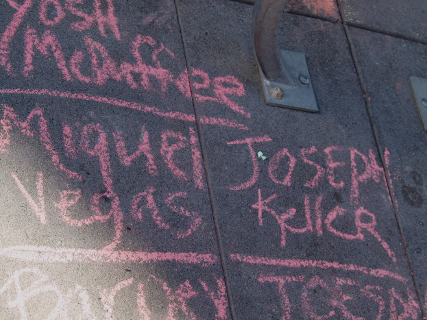 Ein Gehweg mit pinker Kreide-Graffiti und einem Metallobjekt auf der rechten Seite.
